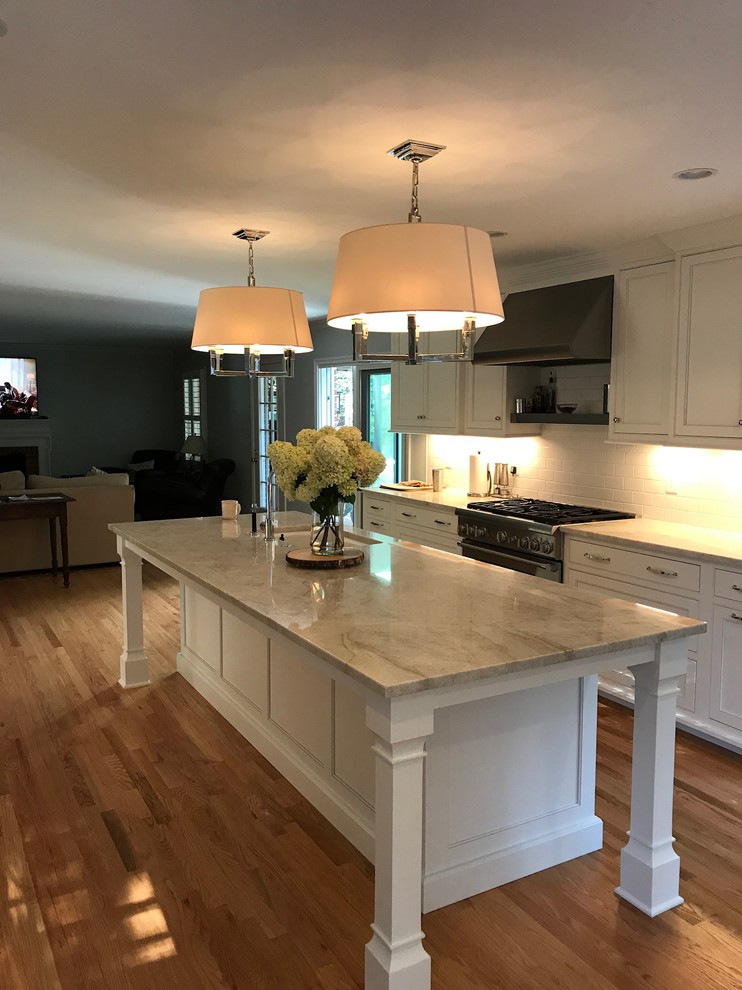 This is an example of a large traditional eat-in kitchen in Baltimore with an undermount sink, beaded inset cabinets, white cabinets, quartzite benchtops, white splashback, ceramic splashback, stainless steel appliances, light hardwood floors and with island.
