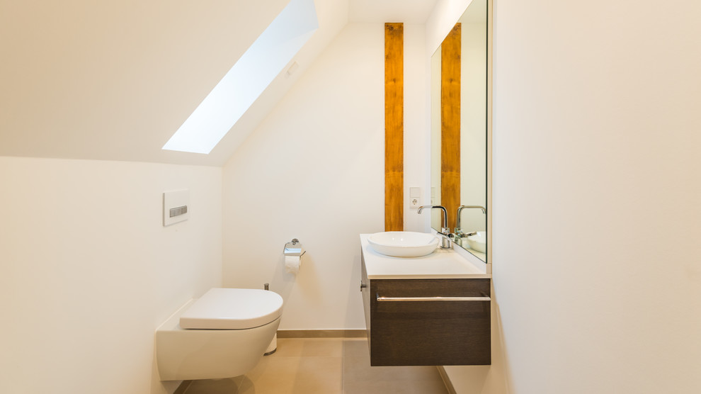 Small contemporary powder room in Other with dark wood cabinets, white walls, a trough sink, beige floor, flat-panel cabinets, a wall-mount toilet and ceramic floors.