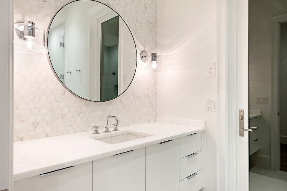 This is an example of a mid-sized transitional kids bathroom in Other with flat-panel cabinets, white cabinets, gray tile, white walls, light hardwood floors, an undermount sink, marble benchtops, beige floor and white benchtops.