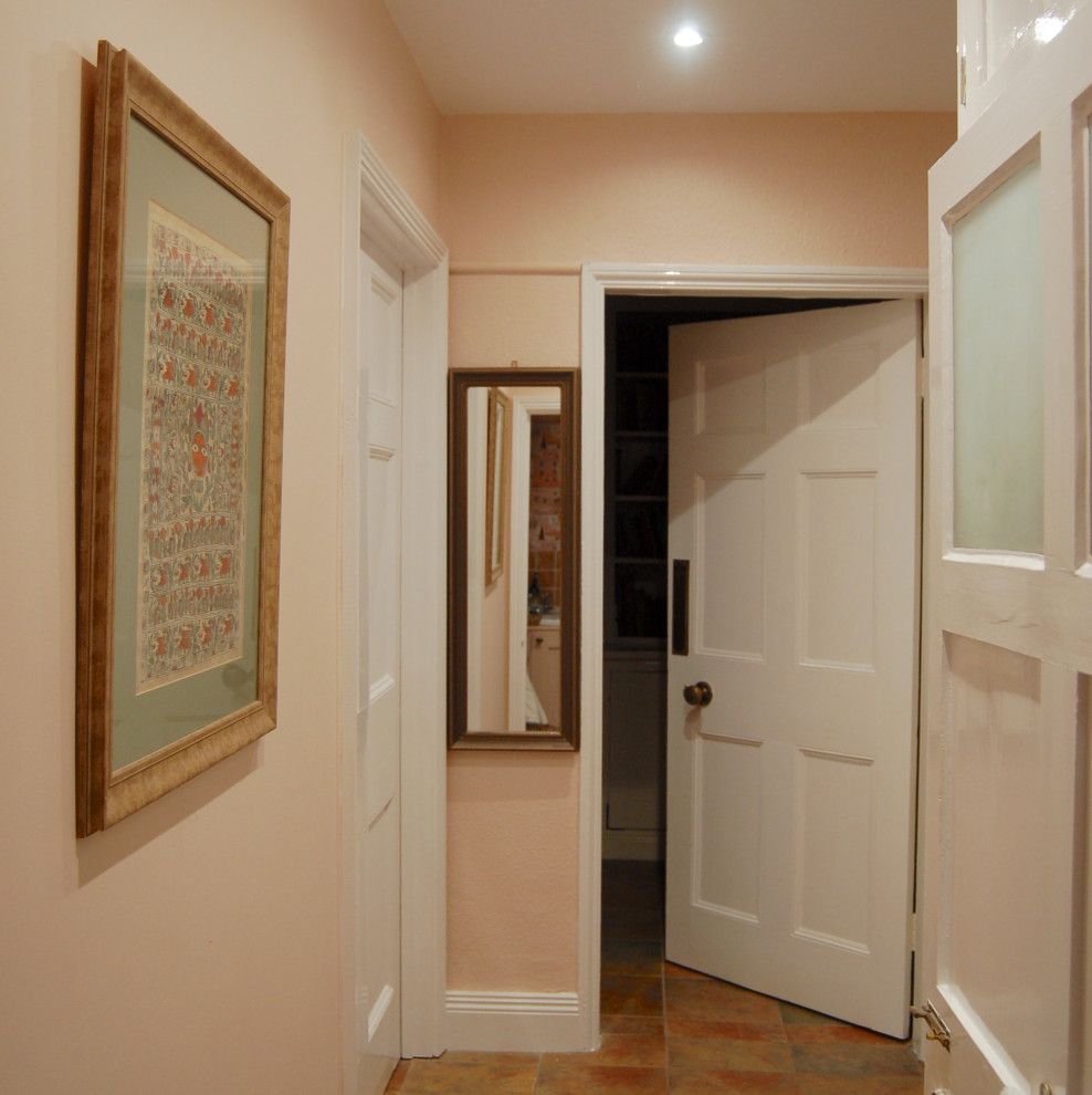 Foto på ett litet rustikt rosa toalett, med luckor med infälld panel, en toalettstol med hel cisternkåpa, rosa kakel, keramikplattor, rosa väggar, klinkergolv i keramik, ett väggmonterat handfat, träbänkskiva och orange golv