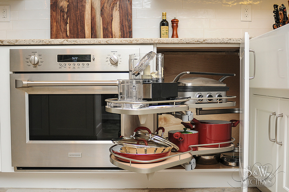 Inspiration for a mid-sized transitional galley porcelain tile eat-in kitchen remodel in Tampa with a farmhouse sink, flat-panel cabinets, white cabinets, quartz countertops, white backsplash, subway tile backsplash, stainless steel appliances and a peninsula