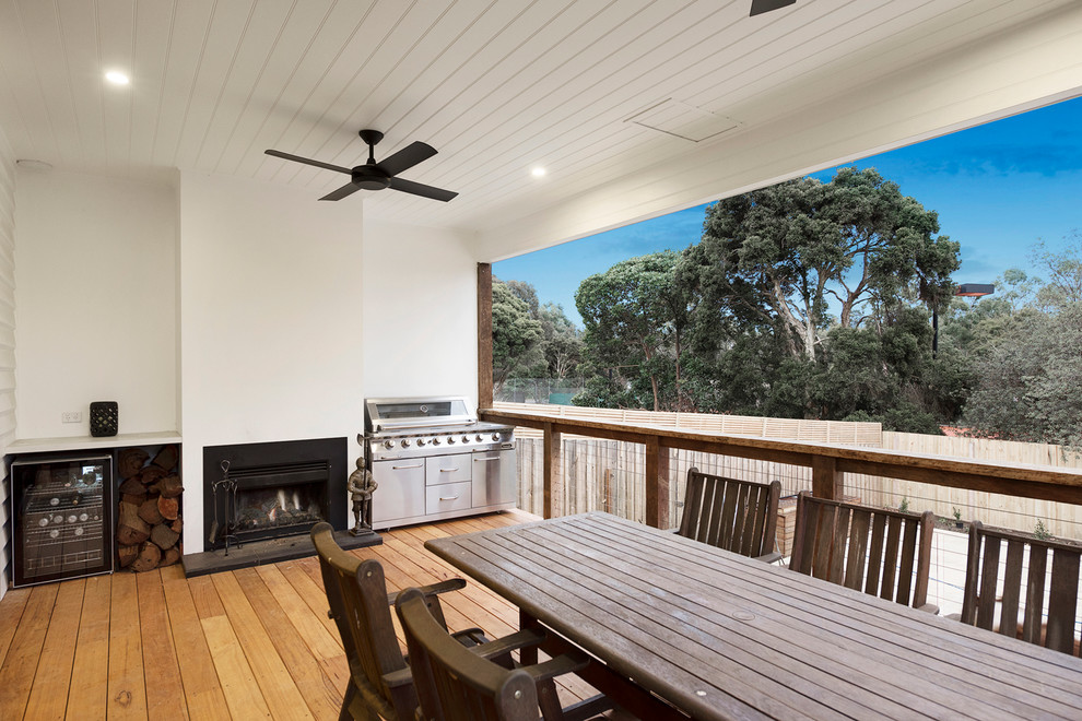 This is an example of a large contemporary backyard deck in Melbourne with a fire feature and a roof extension.