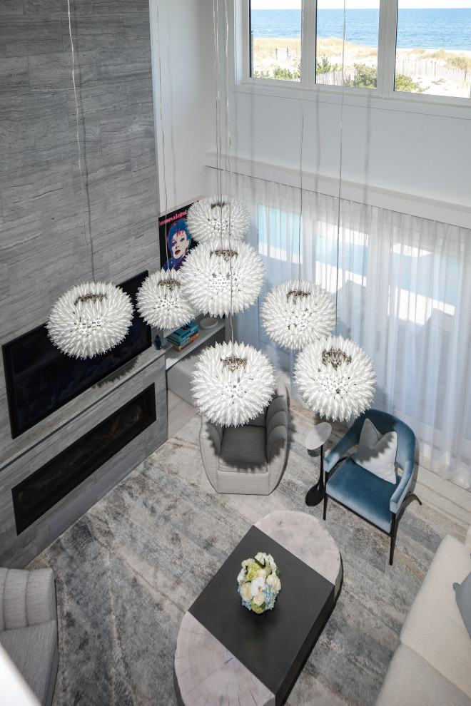 На фото: гостиная комната в морском стиле с серыми стенами, стандартным камином, телевизором на стене и фасадом камина из плитки с