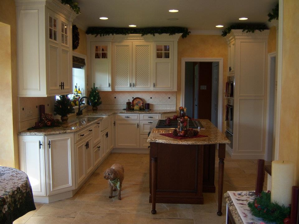 This is an example of a traditional u-shaped eat-in kitchen in Denver with a farmhouse sink, recessed-panel cabinets, white cabinets, granite benchtops, beige splashback, stone tile splashback and panelled appliances.