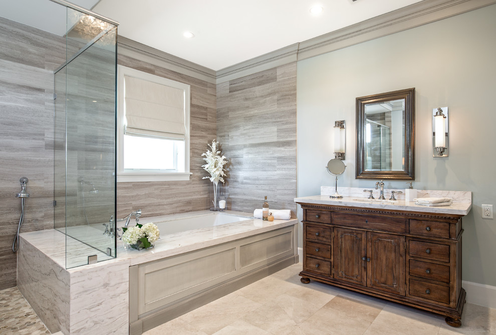 This is an example of a mid-sized beach style master bathroom in Miami with furniture-like cabinets, medium wood cabinets, an undermount tub, a corner shower, a one-piece toilet, white tile, stone tile, grey walls, marble floors, an undermount sink and marble benchtops.