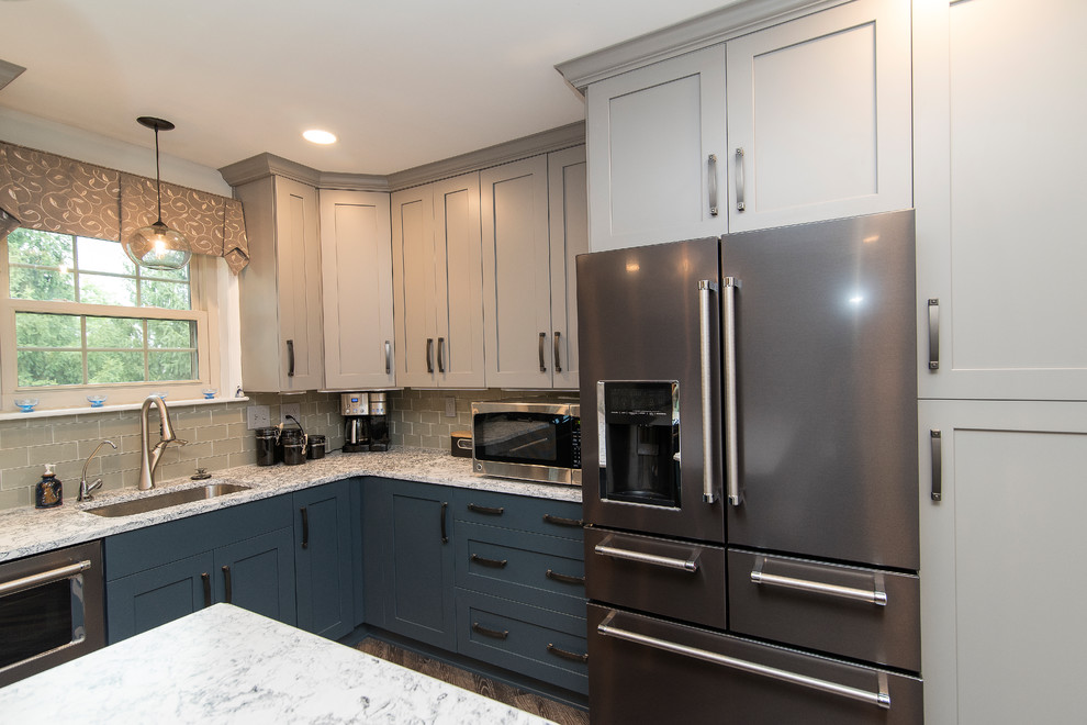 Example of a mid-sized transitional l-shaped brown floor eat-in kitchen design in Baltimore with a single-bowl sink, shaker cabinets, gray cabinets, quartz countertops, gray backsplash, subway tile backsplash, stainless steel appliances, an island and white countertops