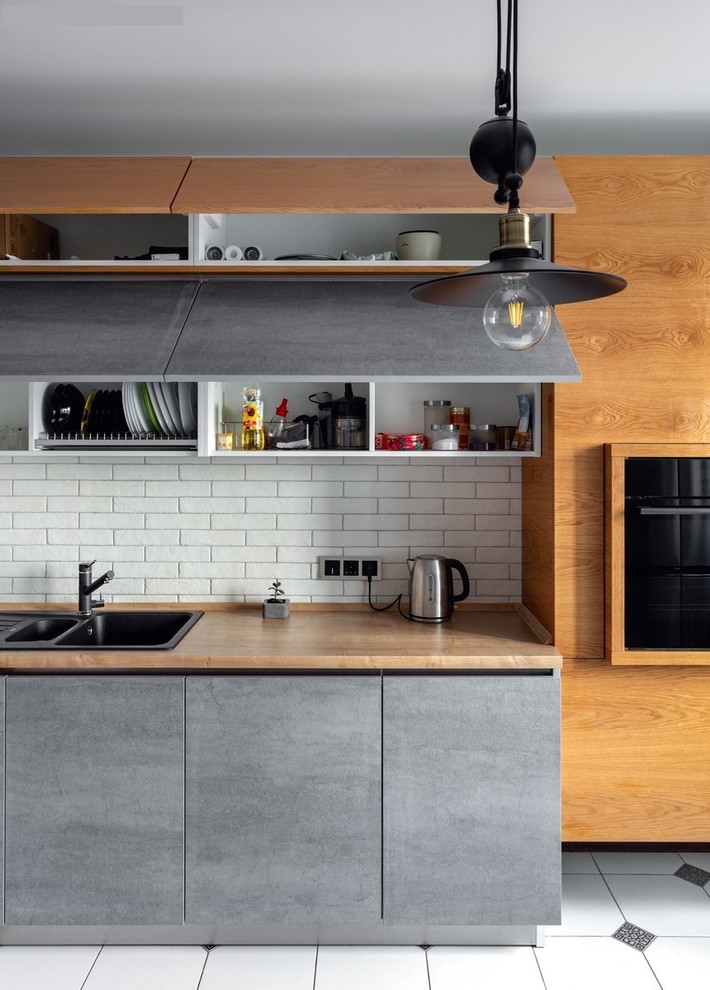 Photo of a small contemporary l-shaped separate kitchen in Moscow with laminate benchtops, white splashback, brick splashback, black appliances, ceramic floors and no island.