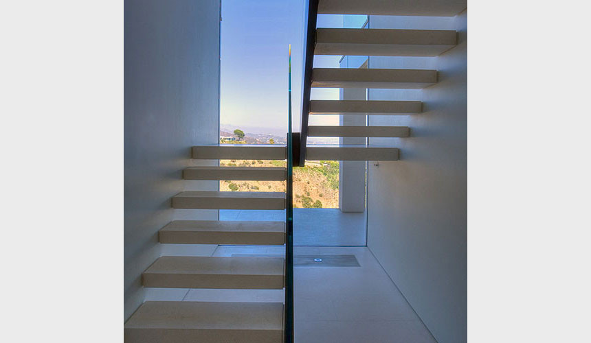 Mid-sized contemporary u-shaped staircase in Los Angeles with open risers and glass railing.