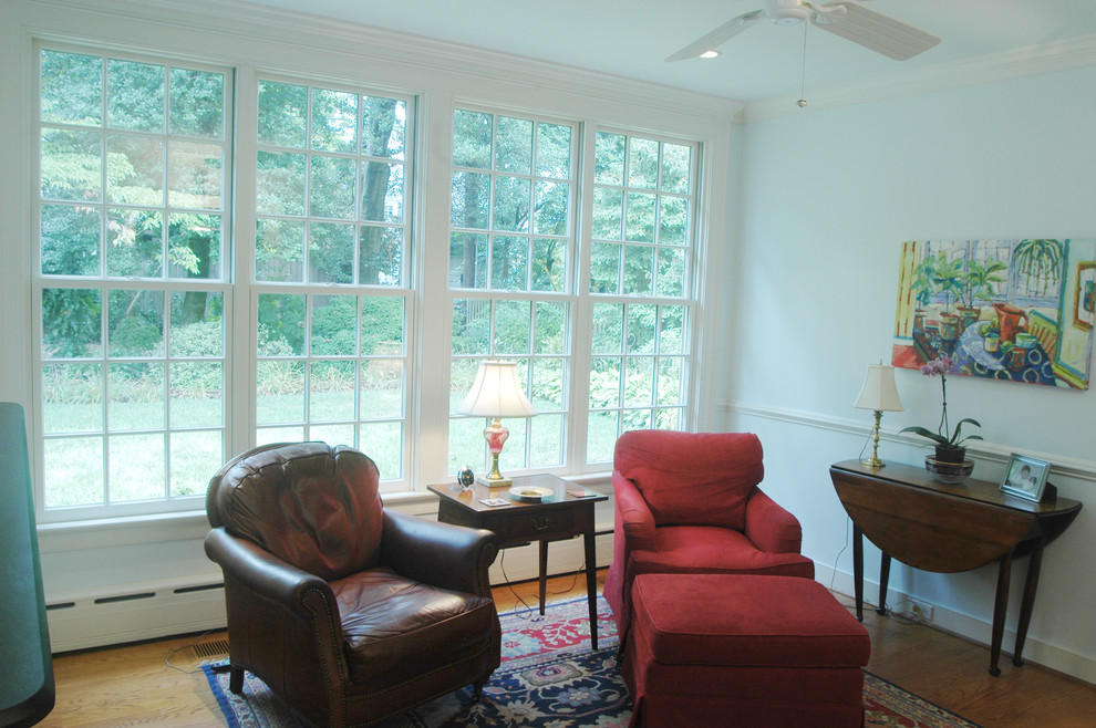 This is an example of a mid-sized traditional family room in Richmond with blue walls, medium hardwood floors, no fireplace, a wall-mounted tv and brown floor.