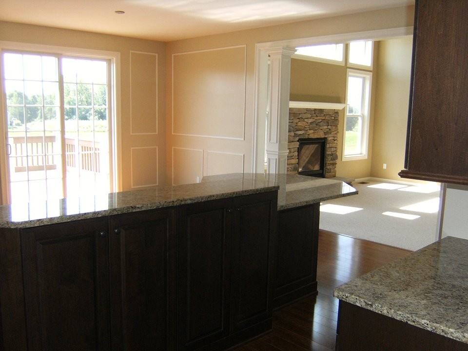 Example of a large transitional l-shaped dark wood floor eat-in kitchen design in New York with an undermount sink, raised-panel cabinets, white cabinets, granite countertops, beige backsplash, stainless steel appliances and an island