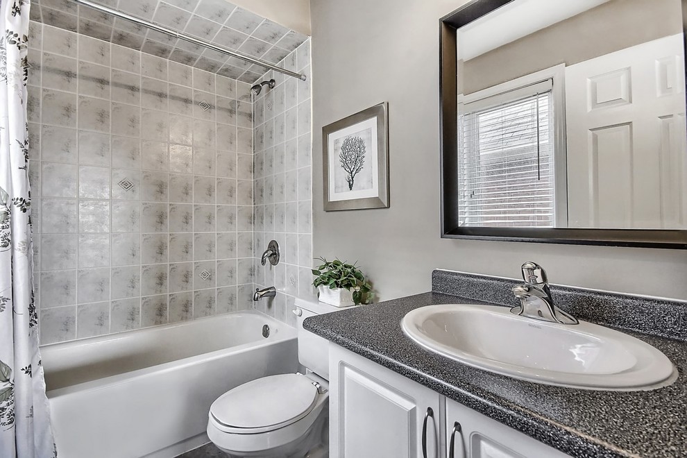 Design ideas for a mid-sized transitional master bathroom in Toronto with a drop-in sink, raised-panel cabinets, white cabinets, an alcove tub, a shower/bathtub combo, a one-piece toilet, gray tile and grey walls.