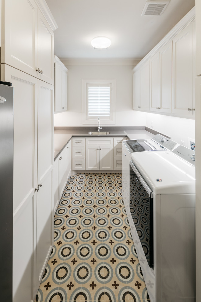 Design ideas for an expansive transitional u-shaped dedicated laundry room in Houston with a single-bowl sink, white cabinets, a side-by-side washer and dryer, shaker cabinets, white walls, ceramic floors, multi-coloured floor and grey benchtop.