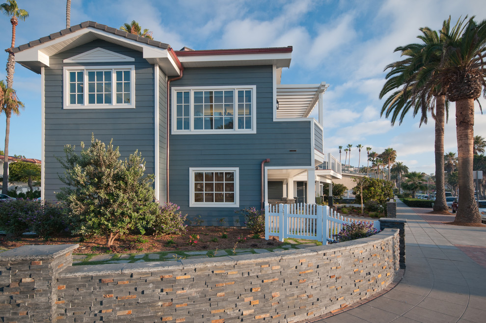 Large beach style two-storey blue house exterior in San Diego with wood siding and a gable roof.