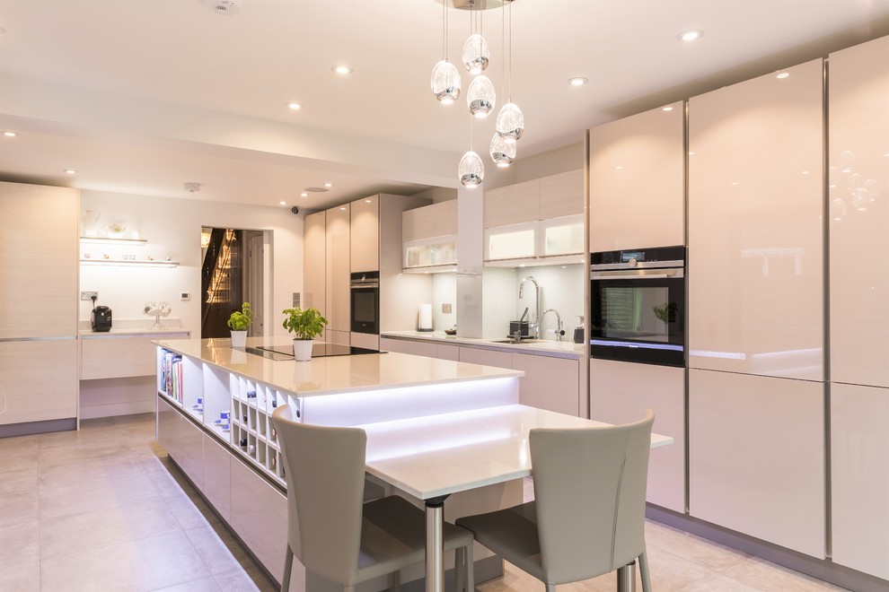 Photo of an expansive modern separate kitchen in London with a single-bowl sink, glass-front cabinets, beige cabinets, quartzite benchtops, white splashback, glass sheet splashback, black appliances, porcelain floors and with island.