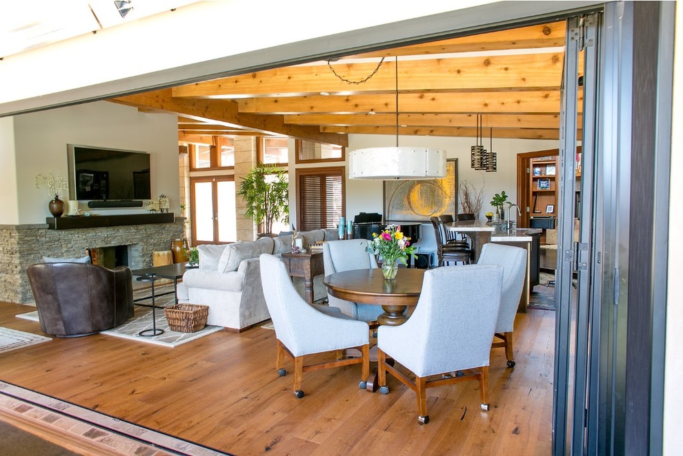 This is an example of a large midcentury open concept living room in San Diego with a music area, medium hardwood floors, a two-sided fireplace, a stone fireplace surround and a wall-mounted tv.