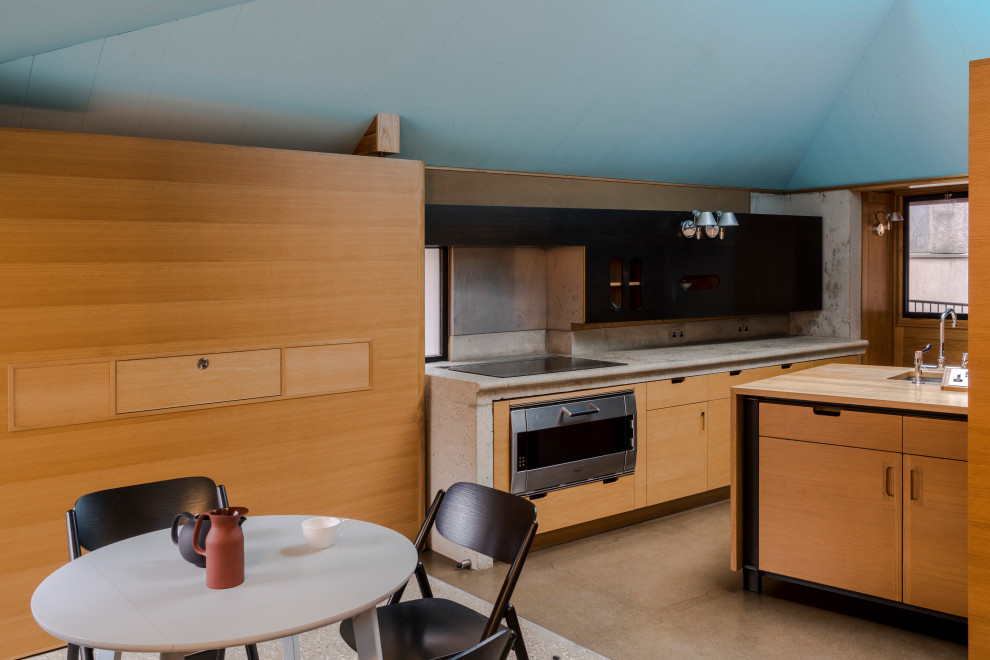 Contemporary l-shaped eat-in kitchen in London with an undermount sink, flat-panel cabinets, light wood cabinets, stainless steel appliances, concrete floors, a peninsula, beige floor, beige benchtop and vaulted.
