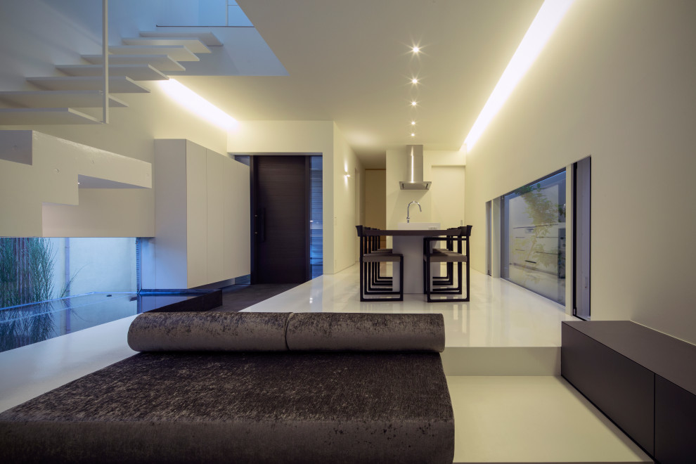 Ejemplo de salón abierto moderno pequeño con paredes blancas, televisor colgado en la pared y suelo blanco
