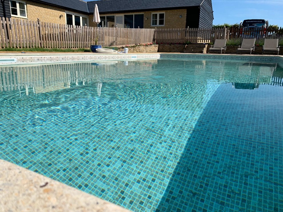 Design ideas for a mid-sized country courtyard rectangular pool in West Midlands with natural stone pavers.