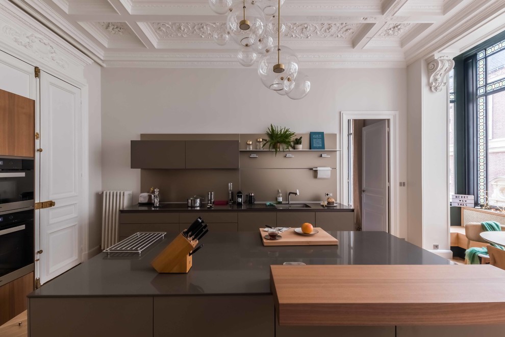 Geschlossene, Zweizeilige Moderne Küche mit braunen Schränken, hellem Holzboden, Kücheninsel und beigem Boden in Paris