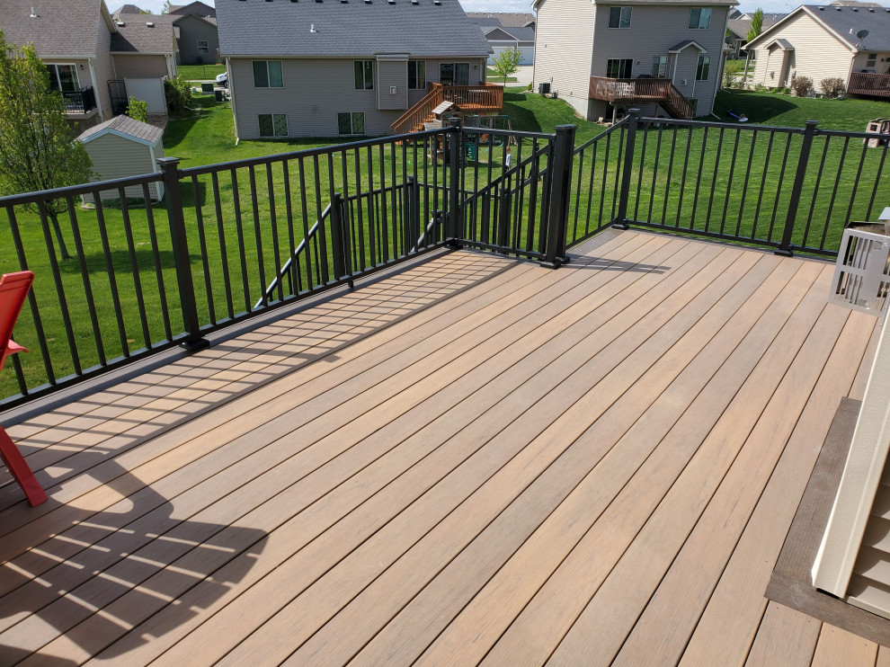 Large backyard second story metal railing deck photo with a roof extension