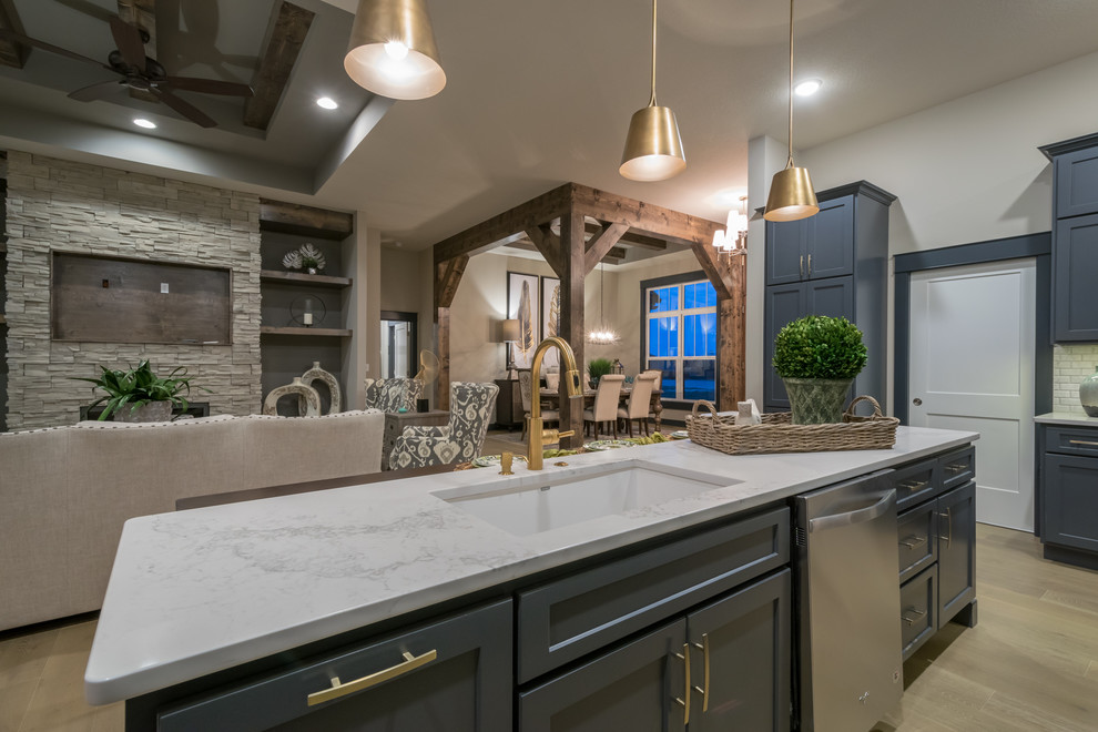 Inspiration for a mid-sized transitional light wood floor kitchen remodel with an undermount sink, recessed-panel cabinets, blue cabinets, quartzite countertops, white backsplash, cement tile backsplash, stainless steel appliances and an island
