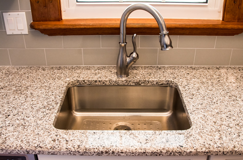 Kitchen - small transitional u-shaped light wood floor kitchen idea in Baltimore with an undermount sink, raised-panel cabinets, white cabinets and no island