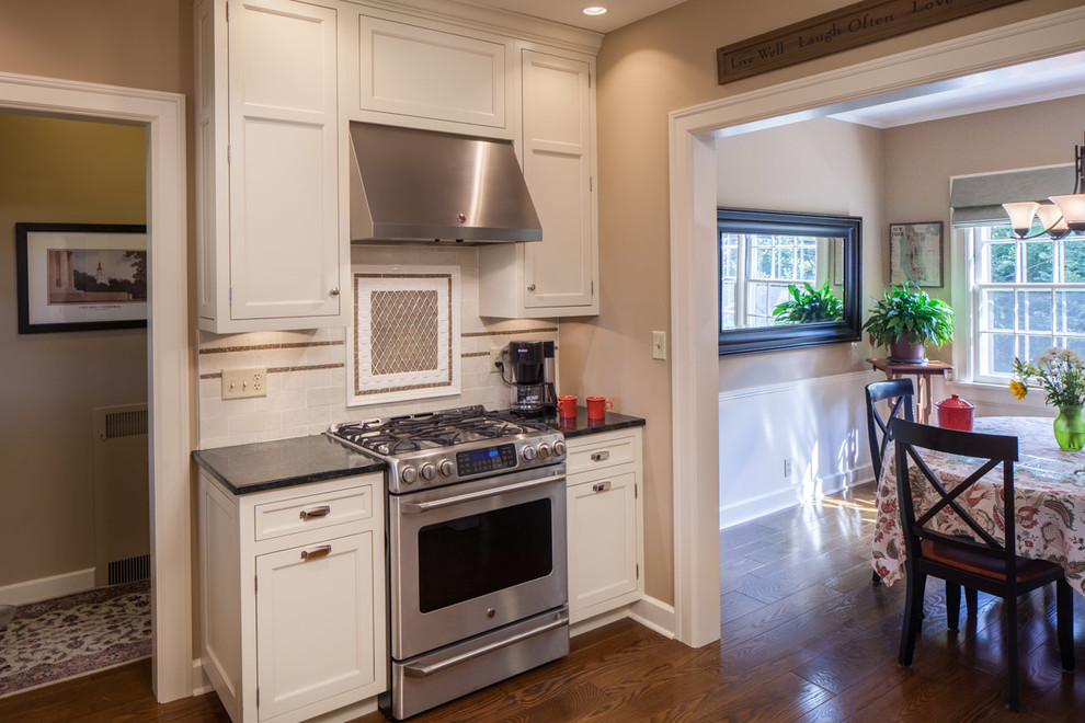 Enclosed kitchen - mid-sized transitional single-wall medium tone wood floor enclosed kitchen idea with an undermount sink, beaded inset cabinets, white cabinets, granite countertops, white backsplash, porcelain backsplash, stainless steel appliances and no island