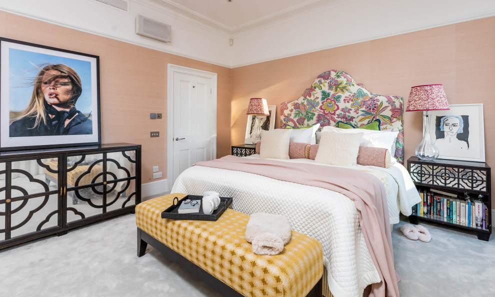 На фото: большая хозяйская спальня в стиле фьюжн с розовыми стенами, ковровым покрытием, стандартным камином, фасадом камина из дерева, серым полом и обоями на стенах с
