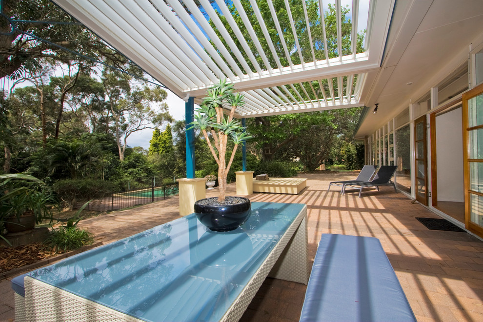 This is an example of a contemporary courtyard patio in Sydney with tile and a pergola.