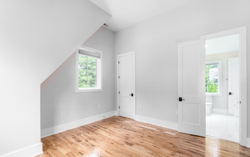 Diseño de habitación de invitados contemporánea con paredes blancas, suelo de madera clara y suelo marrón
