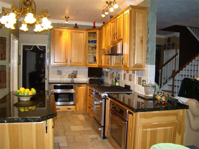 Eat-in kitchen - large transitional l-shaped travertine floor and beige floor eat-in kitchen idea in Houston with raised-panel cabinets, medium tone wood cabinets, granite countertops, beige backsplash, ceramic backsplash, stainless steel appliances and an island