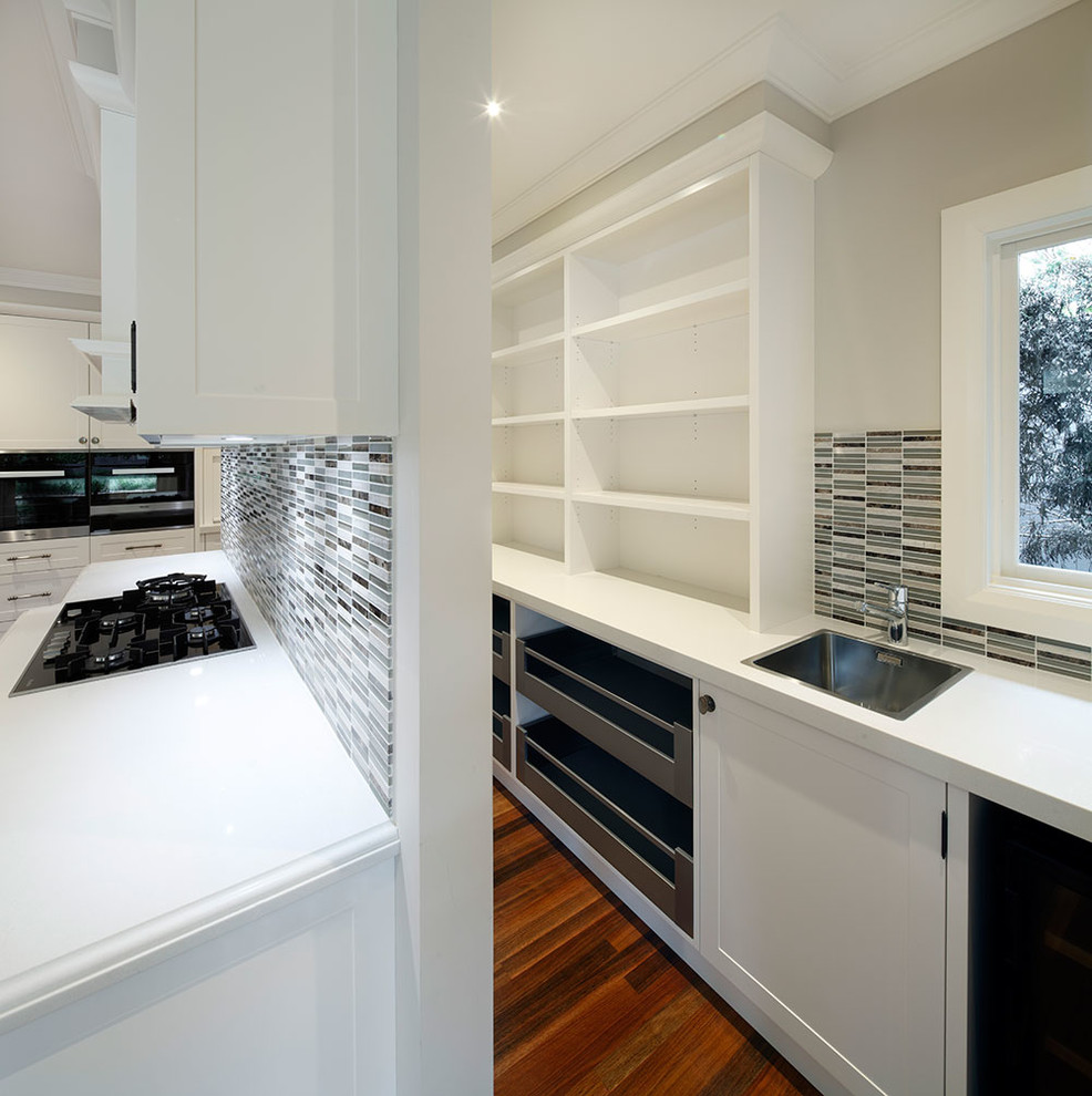 This is an example of a large traditional galley kitchen pantry in Sydney with a double-bowl sink, shaker cabinets, white cabinets, quartz benchtops, panelled appliances, medium hardwood floors and with island.