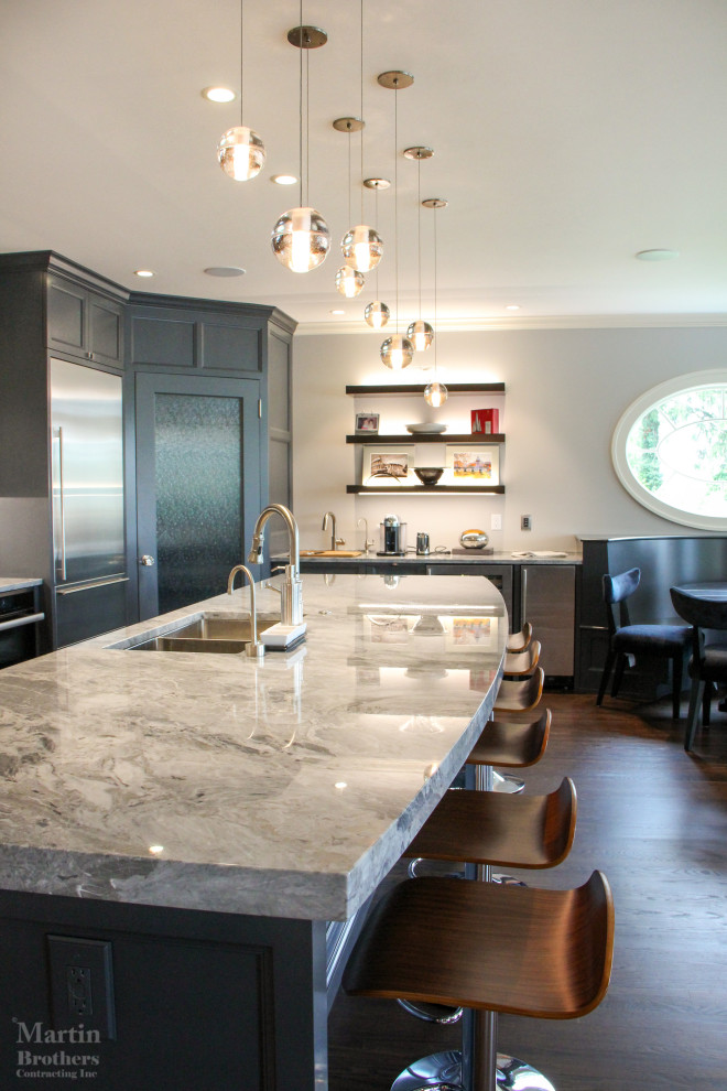 Large transitional single-wall medium tone wood floor open concept kitchen photo with a double-bowl sink, recessed-panel cabinets, gray cabinets, marble countertops, multicolored backsplash, stainless steel appliances, an island and marble backsplash