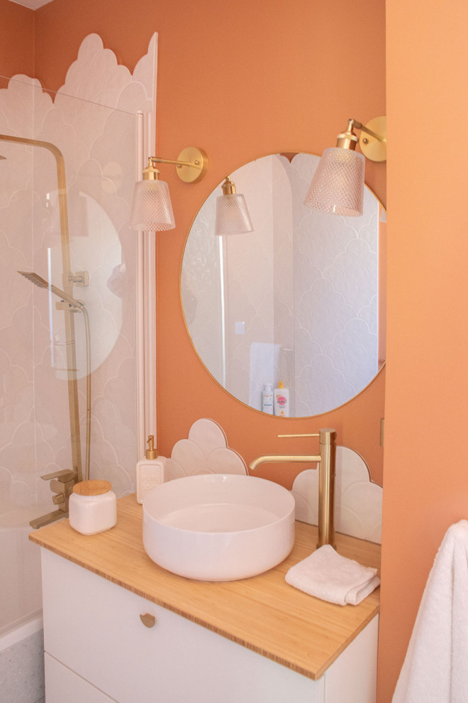 Idee per una piccola stanza da bagno per bambini moderna con vasca sottopiano, WC sospeso, piastrelle bianche, piastrelle in ceramica, pareti arancioni, pavimento alla veneziana, top in legno, pavimento grigio e un lavabo