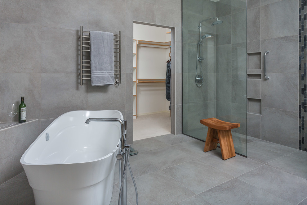 Inspiration for a large transitional master bathroom in Other with flat-panel cabinets, grey cabinets, a freestanding tub, a curbless shower, a one-piece toilet, gray tile, porcelain tile, grey walls, porcelain floors, a wall-mount sink, engineered quartz benchtops, grey floor and an open shower.