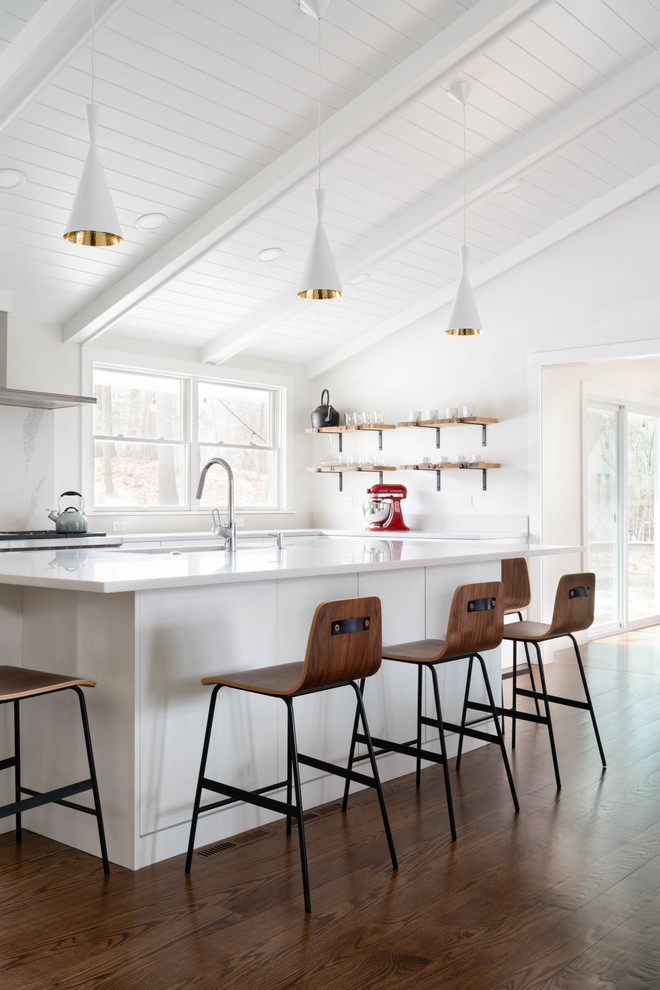 Inspiration for a mid-sized contemporary l-shaped eat-in kitchen in Boston with a single-bowl sink, flat-panel cabinets, white cabinets, quartz benchtops, white splashback, stone slab splashback, stainless steel appliances, dark hardwood floors, with island, brown floor and white benchtop.