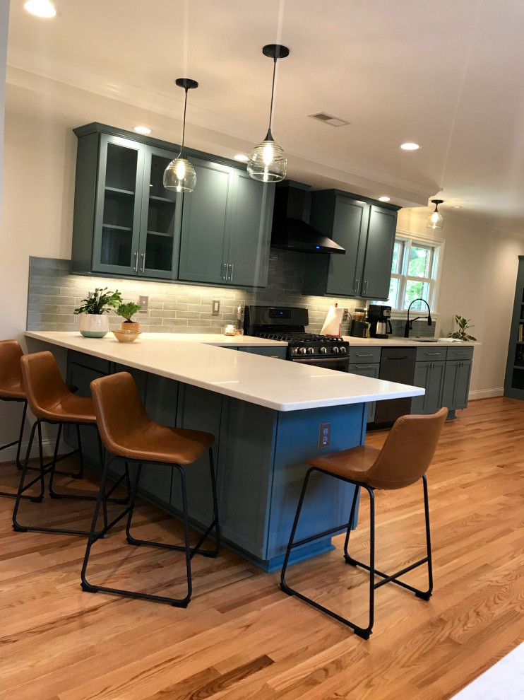 Design ideas for a contemporary u-shaped separate kitchen in Raleigh with a single-bowl sink, flat-panel cabinets, green cabinets, quartzite benchtops, green splashback, cement tile splashback, black appliances, light hardwood floors, no island and white benchtop.