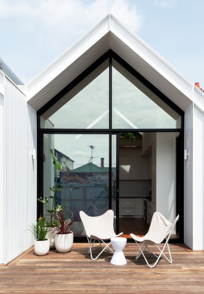 This is an example of a small scandinavian one-storey white house exterior in Melbourne with concrete fiberboard siding, a gable roof and a metal roof.