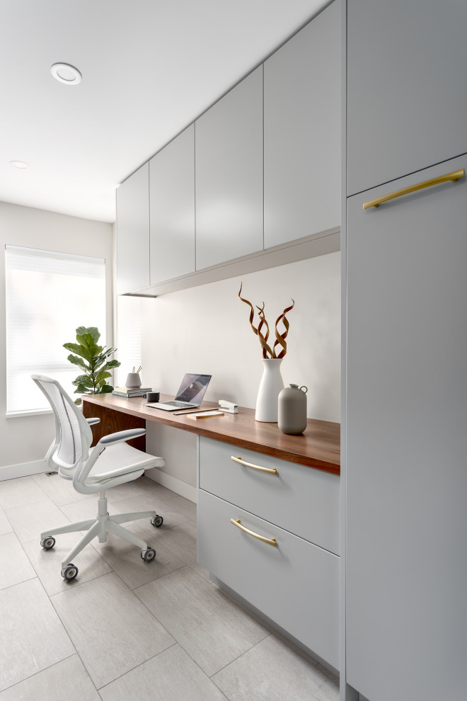 Inredning av ett modernt litet arbetsrum, med vita väggar, klinkergolv i porslin, ett inbyggt skrivbord och grått golv