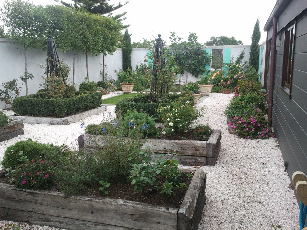 Large country backyard formal garden in Auckland with a container garden and gravel.