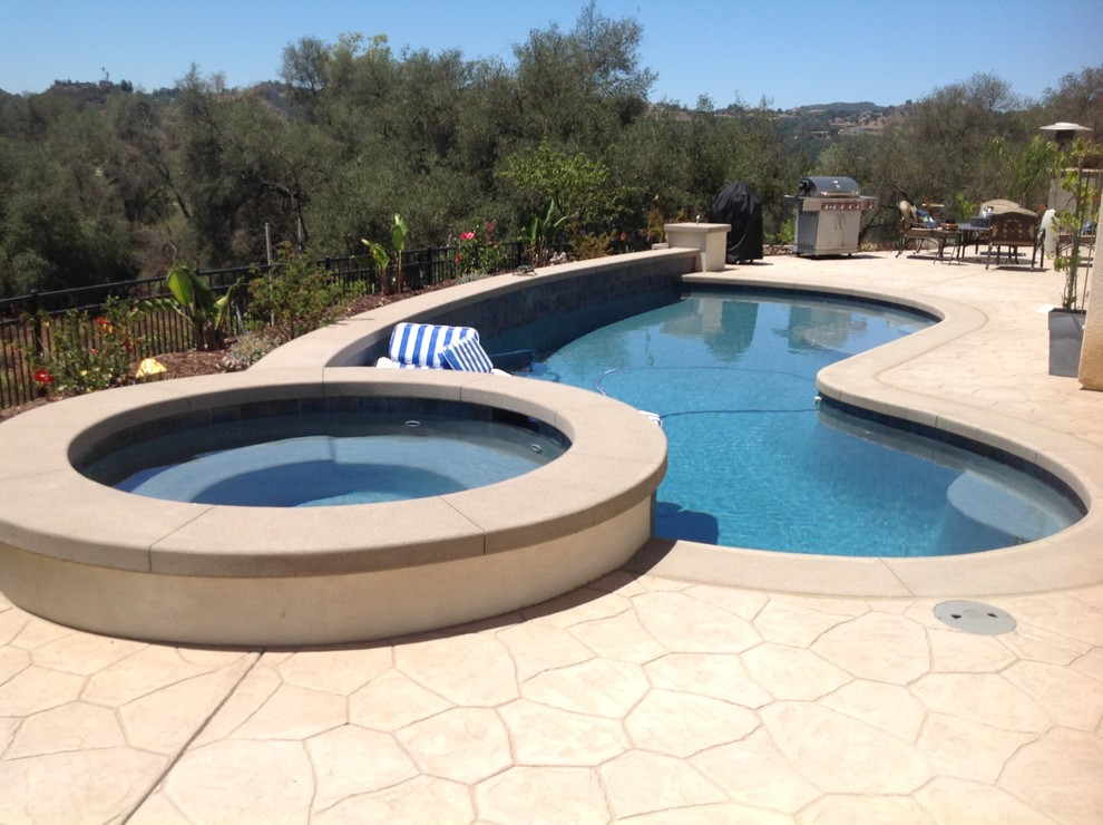 Design ideas for a mid-sized country backyard kidney-shaped lap pool in San Diego with a hot tub and natural stone pavers.