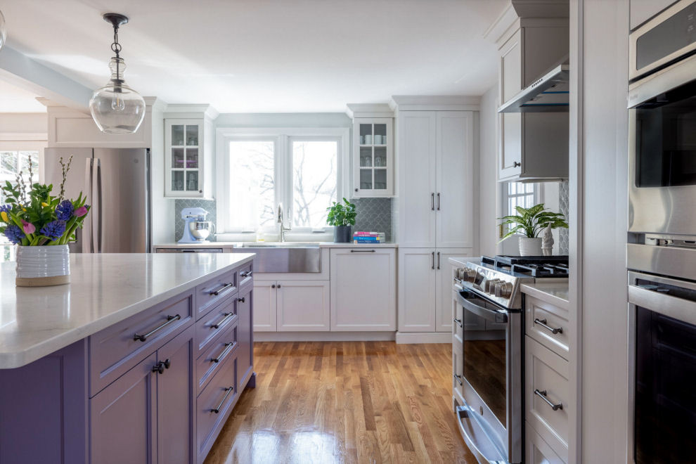Inspiration for a transitional l-shaped kitchen in Boston with a farmhouse sink, shaker cabinets, purple cabinets, quartz benchtops, grey splashback, ceramic splashback, stainless steel appliances, light hardwood floors, with island and white benchtop.
