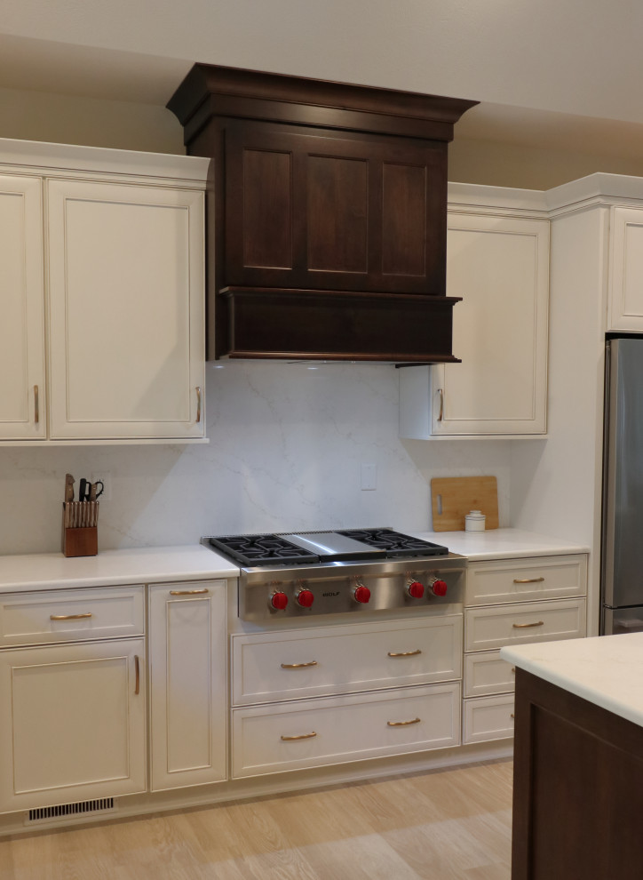 Example of a large transitional l-shaped kitchen design with an undermount sink, recessed-panel cabinets, quartz countertops, white backsplash, quartz backsplash, stainless steel appliances and white countertops