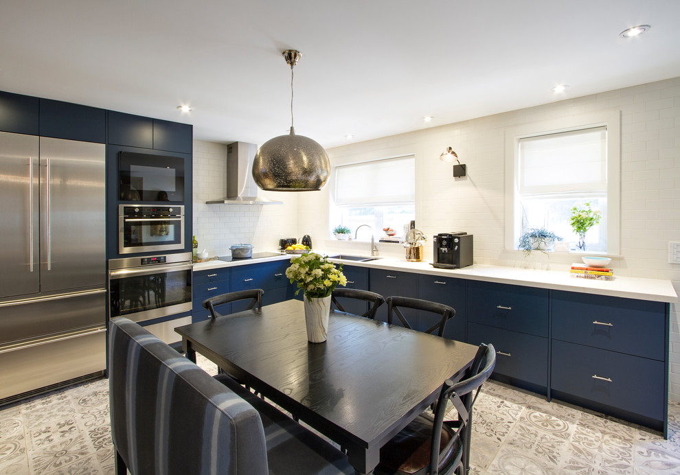 Photo of a mid-sized modern l-shaped eat-in kitchen in Toronto with flat-panel cabinets, blue cabinets, an undermount sink, quartz benchtops, white splashback, subway tile splashback, stainless steel appliances, no island and white benchtop.