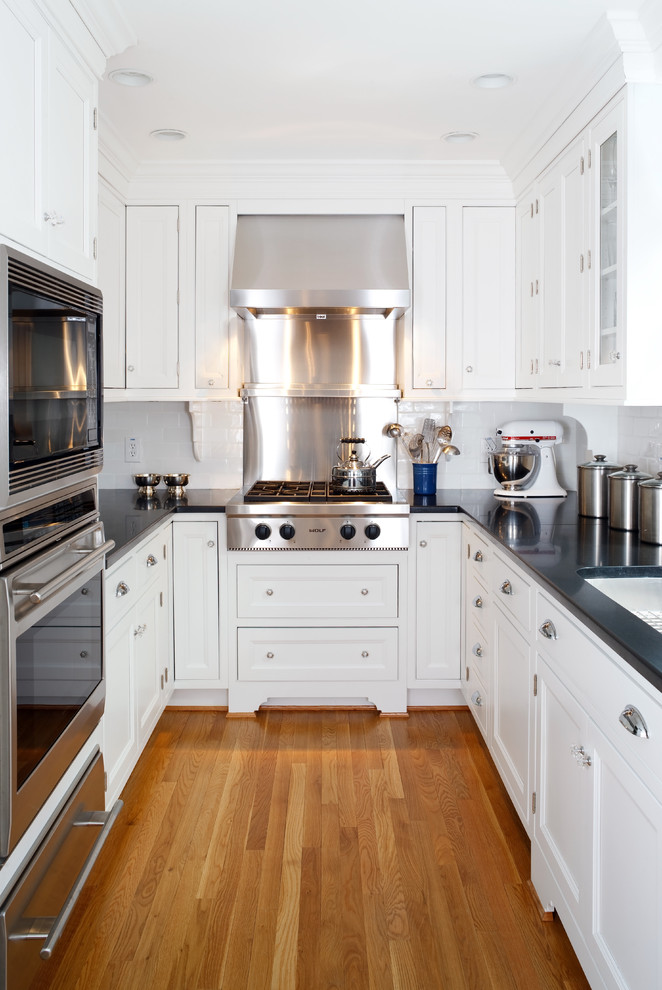 Photo of a traditional separate kitchen in DC Metro with stainless steel appliances, recessed-panel cabinets, white cabinets, white splashback and subway tile splashback.