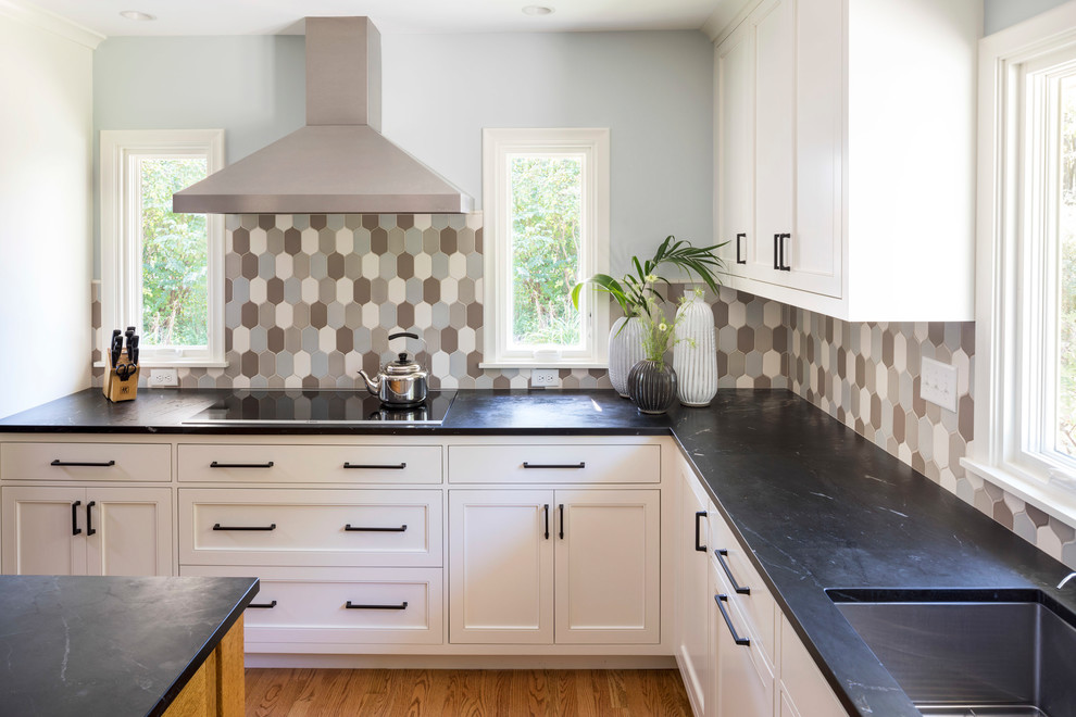 Inspiration for a mid-sized transitional u-shaped medium tone wood floor and brown floor kitchen remodel in Minneapolis with an undermount sink, recessed-panel cabinets, white cabinets, granite countertops, multicolored backsplash, ceramic backsplash, stainless steel appliances and an island