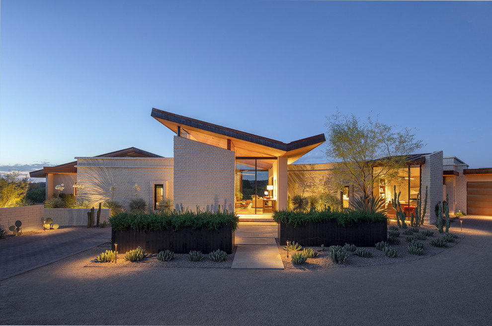 This is an example of a contemporary brick white house exterior in Phoenix with a butterfly roof.