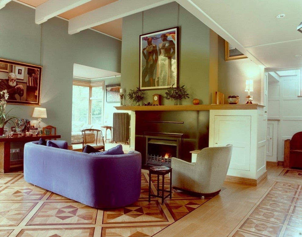 Large modern living room in Kent with green walls, light hardwood flooring, a standard fireplace and a metal fireplace surround.