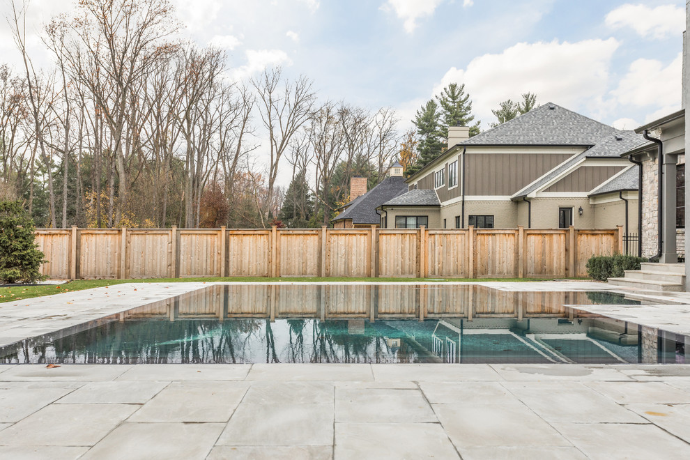 Large backyard concrete paver and custom-shaped infinity pool photo in Indianapolis