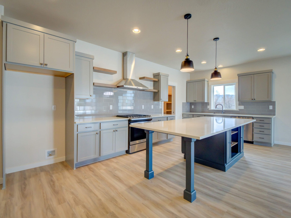 Inspiration for a large transitional l-shaped laminate floor and beige floor eat-in kitchen remodel with an undermount sink, shaker cabinets, gray cabinets, quartz countertops, gray backsplash, ceramic backsplash, stainless steel appliances, an island and white countertops